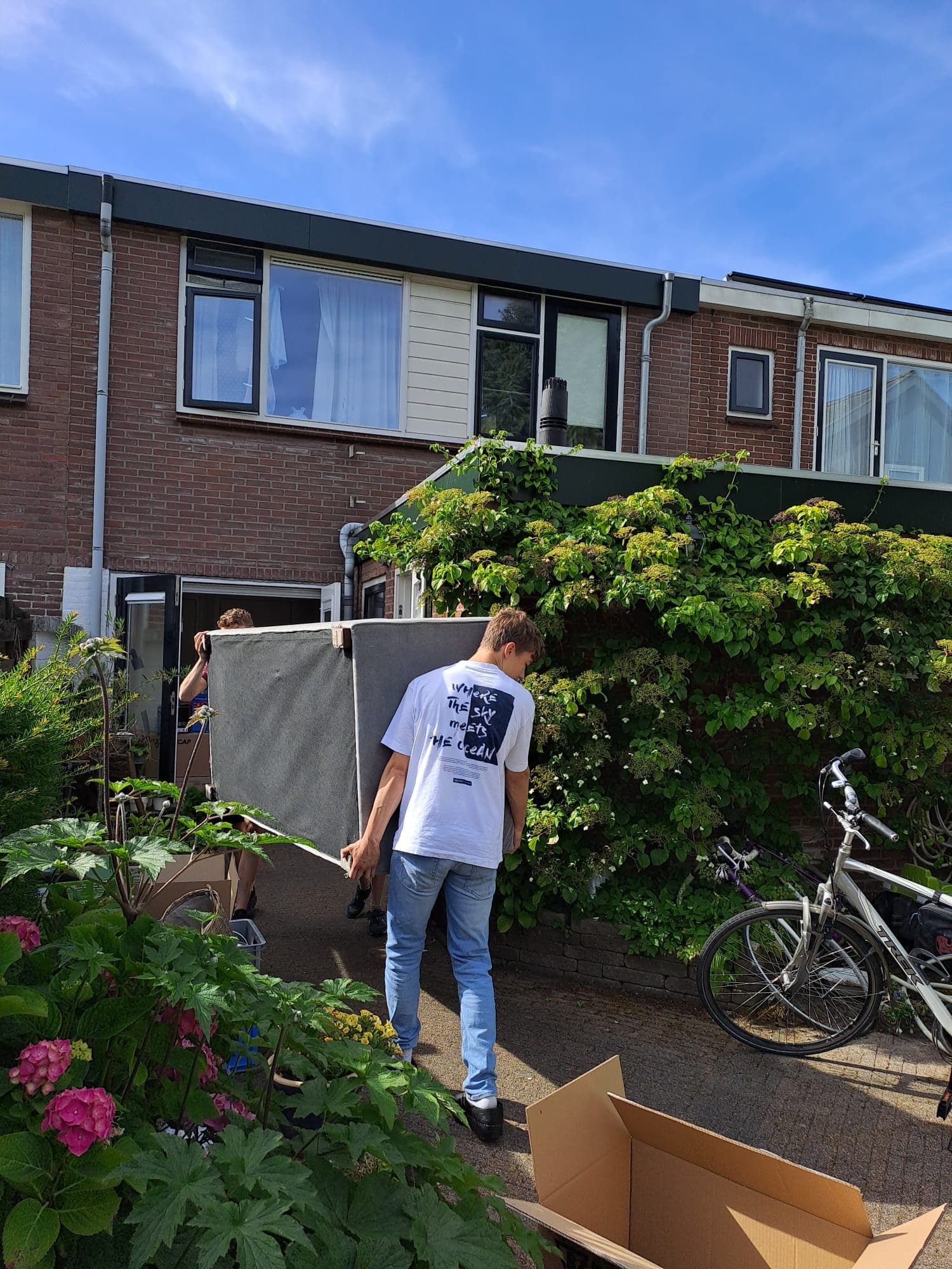 Jongen draagt een kast naar buiten bij het leeghalen van een rijtjeswoning in Middelharnis.